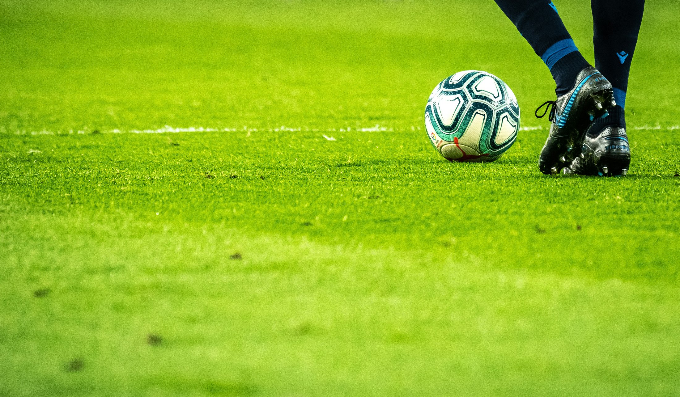 Futbolo kamuolys ir žaidėjo bateliai aikštėje